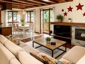 A cozy living room with a fireplace, a television, and a dining area with a table and chairs. - BAQUEIRA URBANIZAC RUDA BLANHIBLAR APARTMENT FOR UP TO 7 PEOPLE (Baqueira)