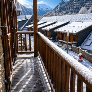 A wooden balcony with a snow-covered roof, overlooking a mountainous landscape with buildings. - BAQUEIRA URBANIZAC RUDA BLANHIBLAR APARTMENT FOR UP TO 7 PEOPLE (Baqueira)