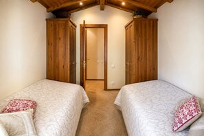 Une chambre avec deux lits, des armoires en bois et un sol recouvert de moquette.