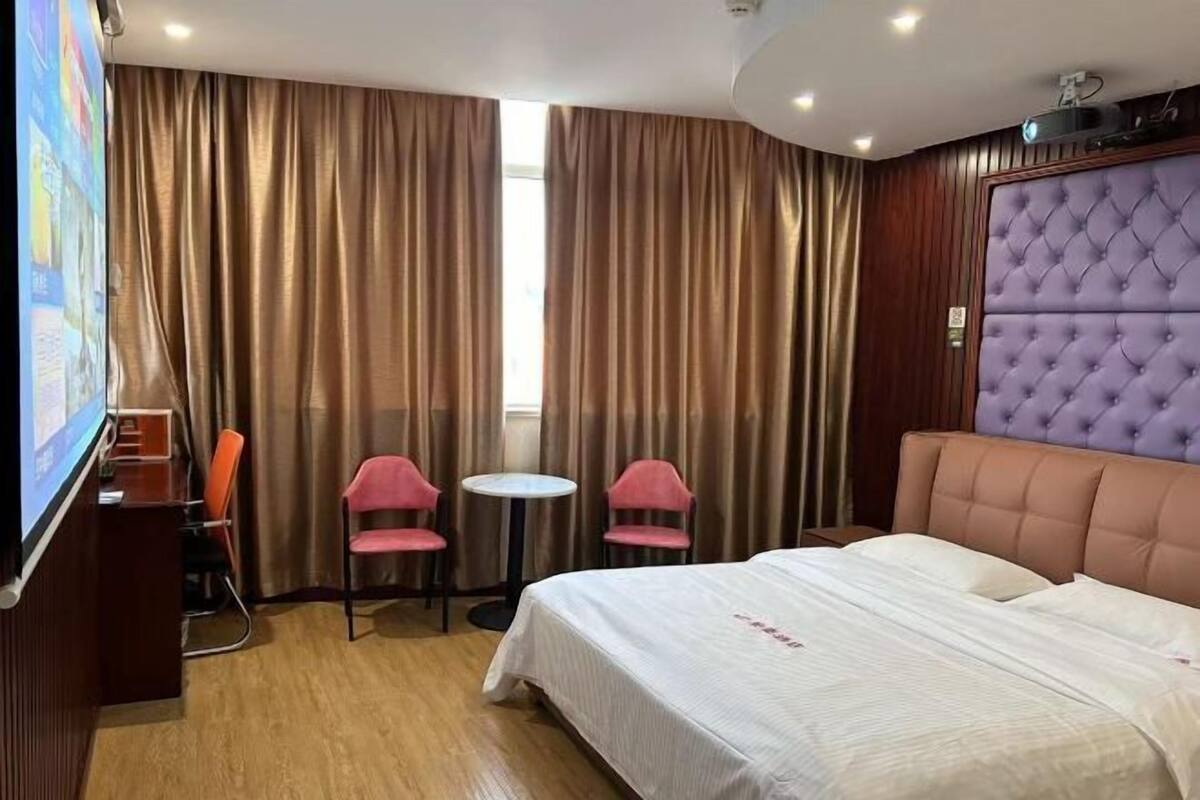 A hotel room with a large bed, a small table, two chairs, and a television.