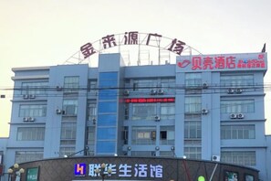 A multi-story building with signage indicating a hotel and a business center. - Shell Hotel (Shanghai Zhang Yan Song Jin Street) (Shanghai)
