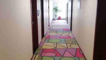 A hotel corridor with doors on both sides and a colorful geometric-patterned floor.