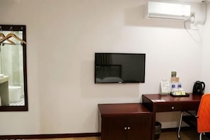A hotel room with a desk, a chair, a television, and a mirror.