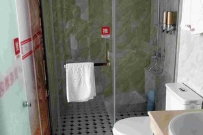 A bathroom with a glass shower enclosure, a white toilet, and a sink with a countertop.