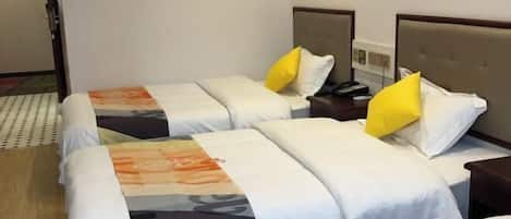 Une chambre d’hôtel avec deux lits, chacun étant équipé de draps blancs et d’une couverture colorée. On y trouve des tables de chevet en bois, avec des lampes et un téléphone.