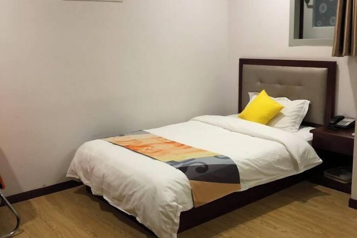 A neatly made bed with a white comforter and a colorful throw blanket.
