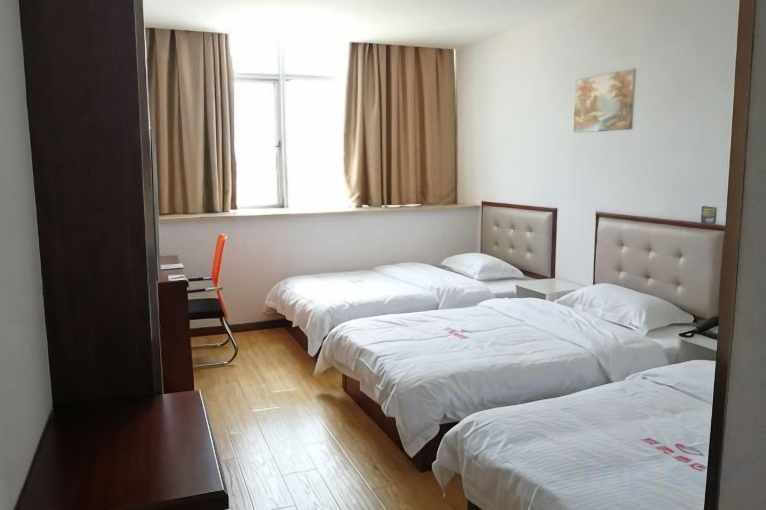 A hotel room with two beds, a desk, and a chair.