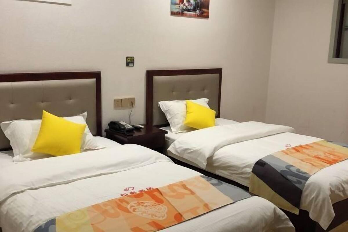 Two single beds with headboards, white bedding, and a yellow pillow on each.