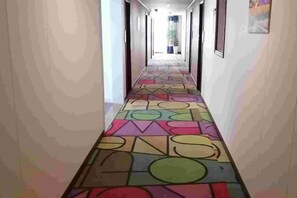 A hallway with a colorful geometric patterned floor, leading to a bright room with a window. - Shell Hotel (Shanghai Zhang Yan Song Jin Street) (Shanghai)