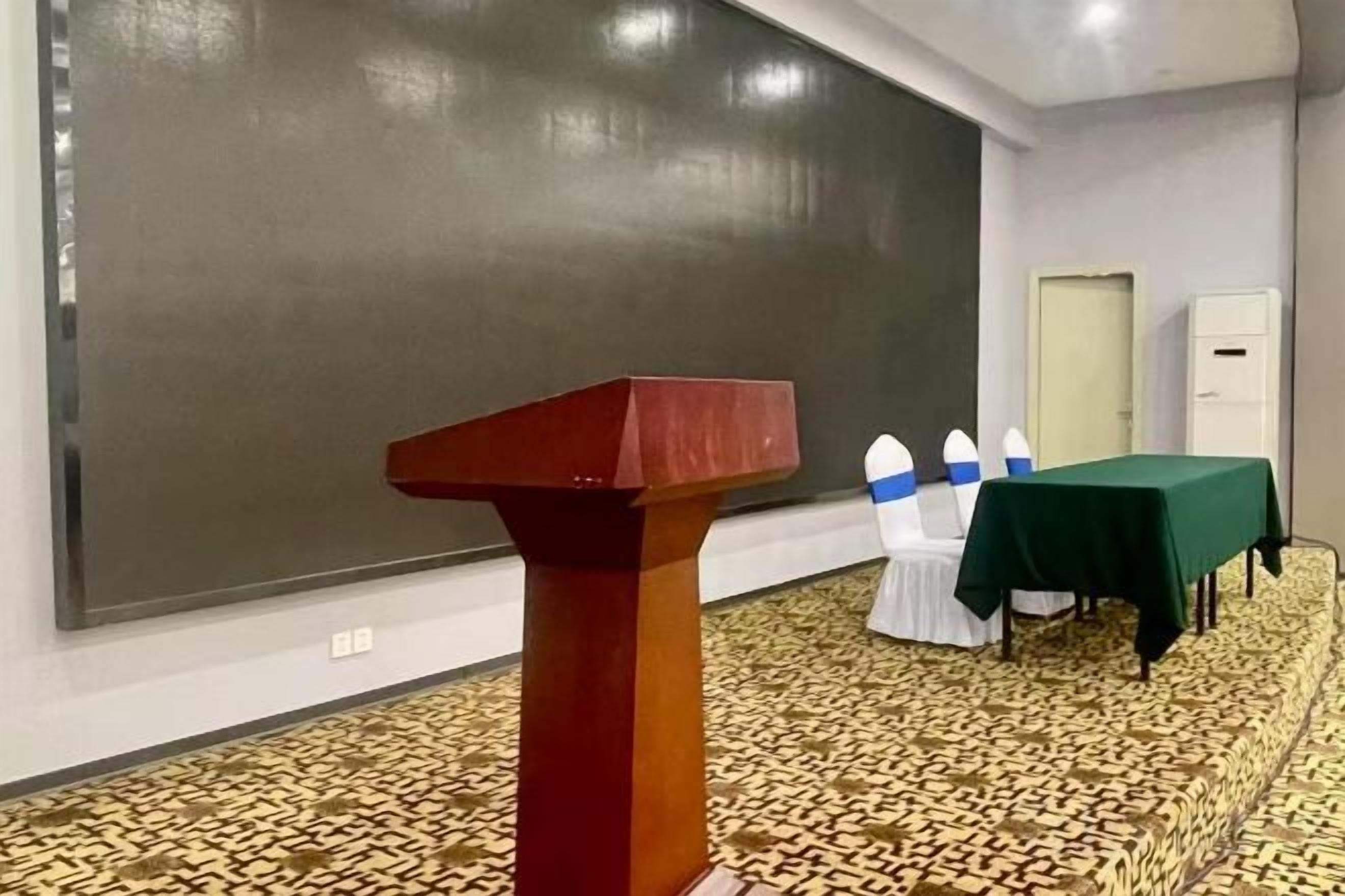 A conference room with a podium, a large blackboard, and a table with a green tablecloth.