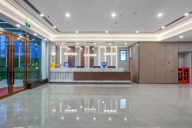 Una moderna área de recepción con acceso de vidrio, un mostrador de recepción con computadoras y un piso limpio y pulido.