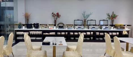 Un área de comedor de hotel con una larga barra, sillas acolchadas y mesas.