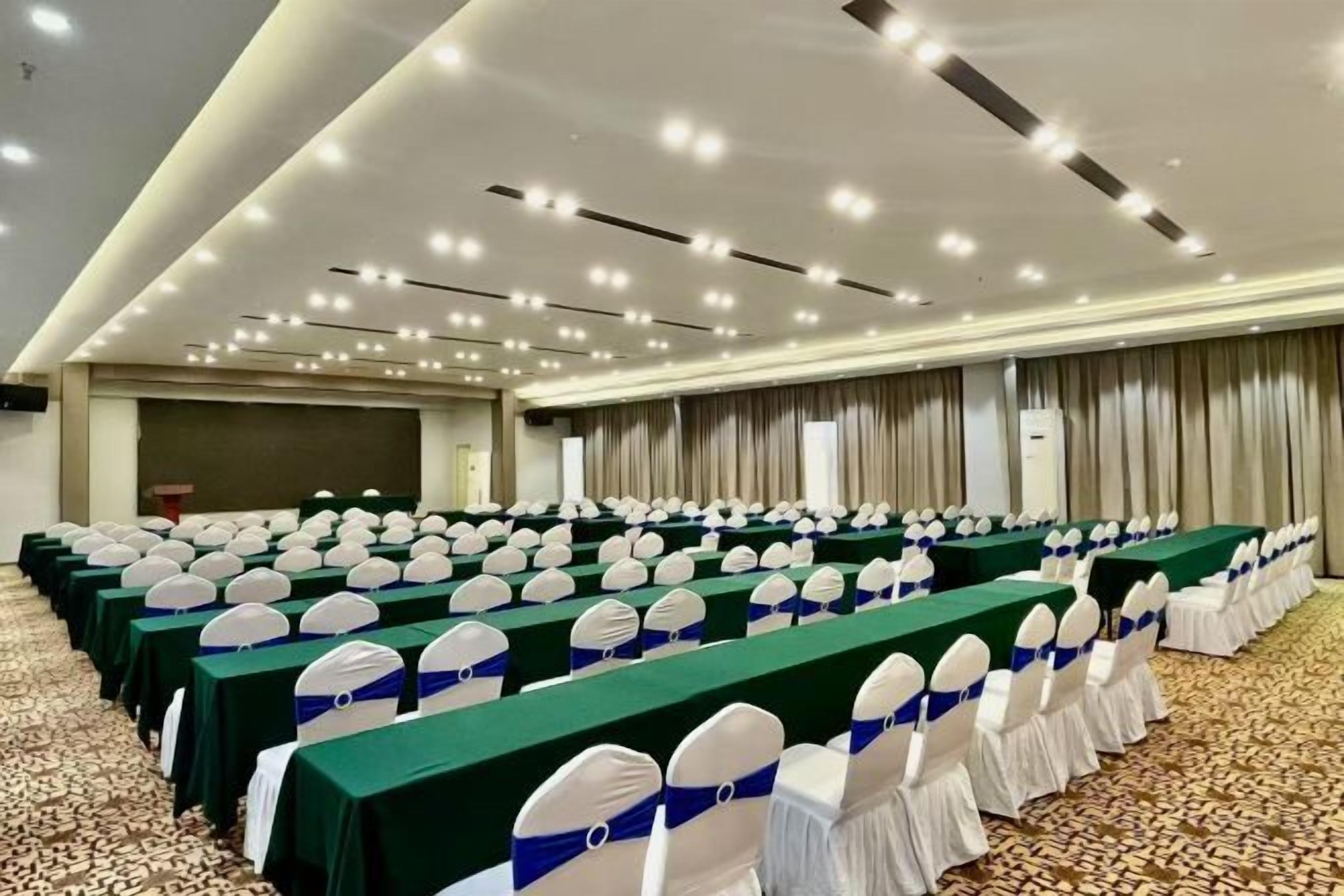 Un salón de conferencias con filas de mesas, sillas y un atril.