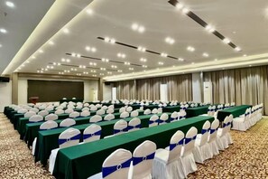Une salle de conférence avec des rangées de tables, de chaises et un pupitre.