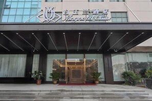 A hotel entrance with a modern facade, a glass door entrance, and potted plants on the steps. - Magnotel Hotel (Yangzhou East High Speed Railway Station) (Yangzhou)