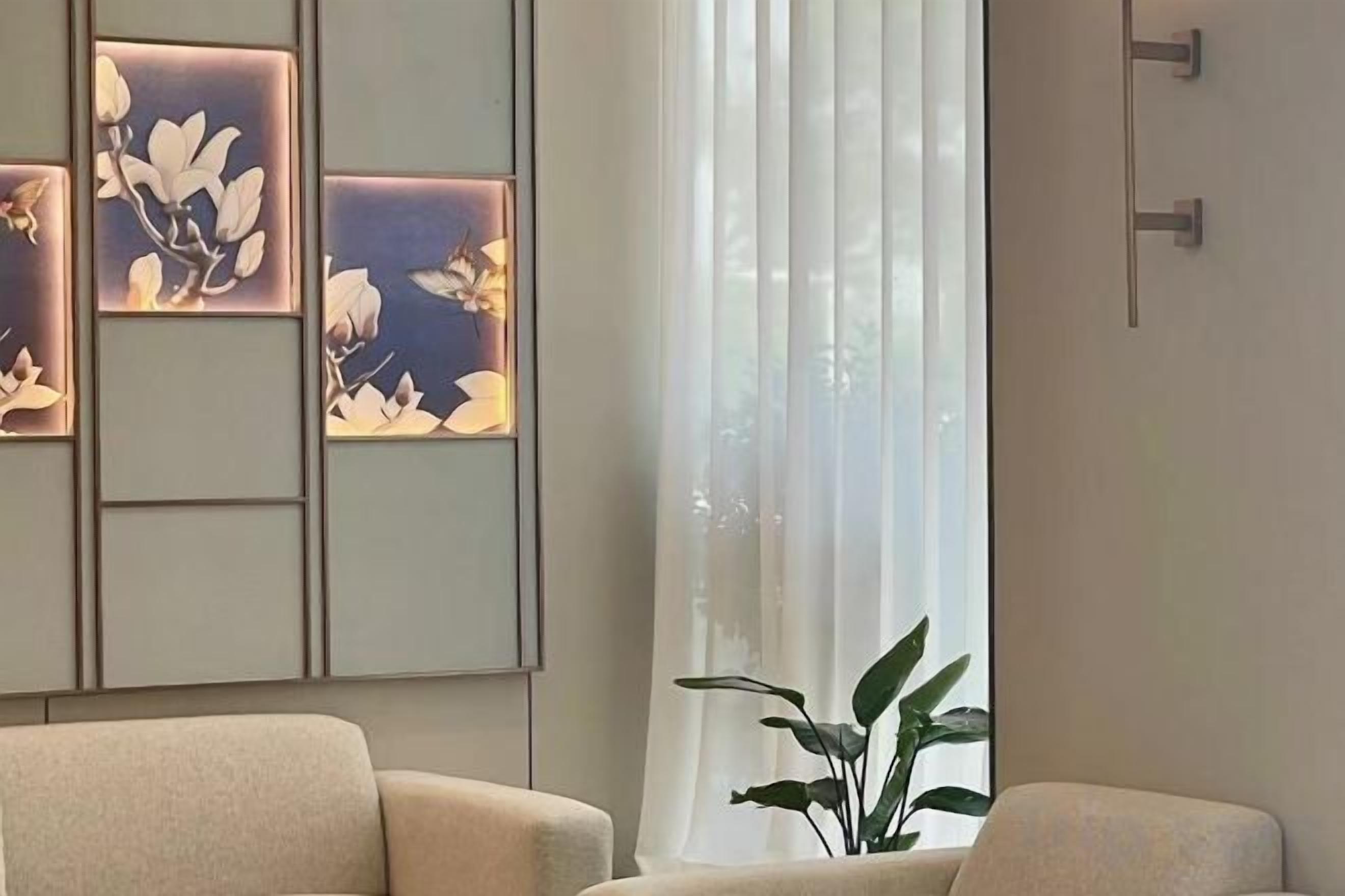 A room with a sofa, a potted plant, and a wall with decorative panels.
