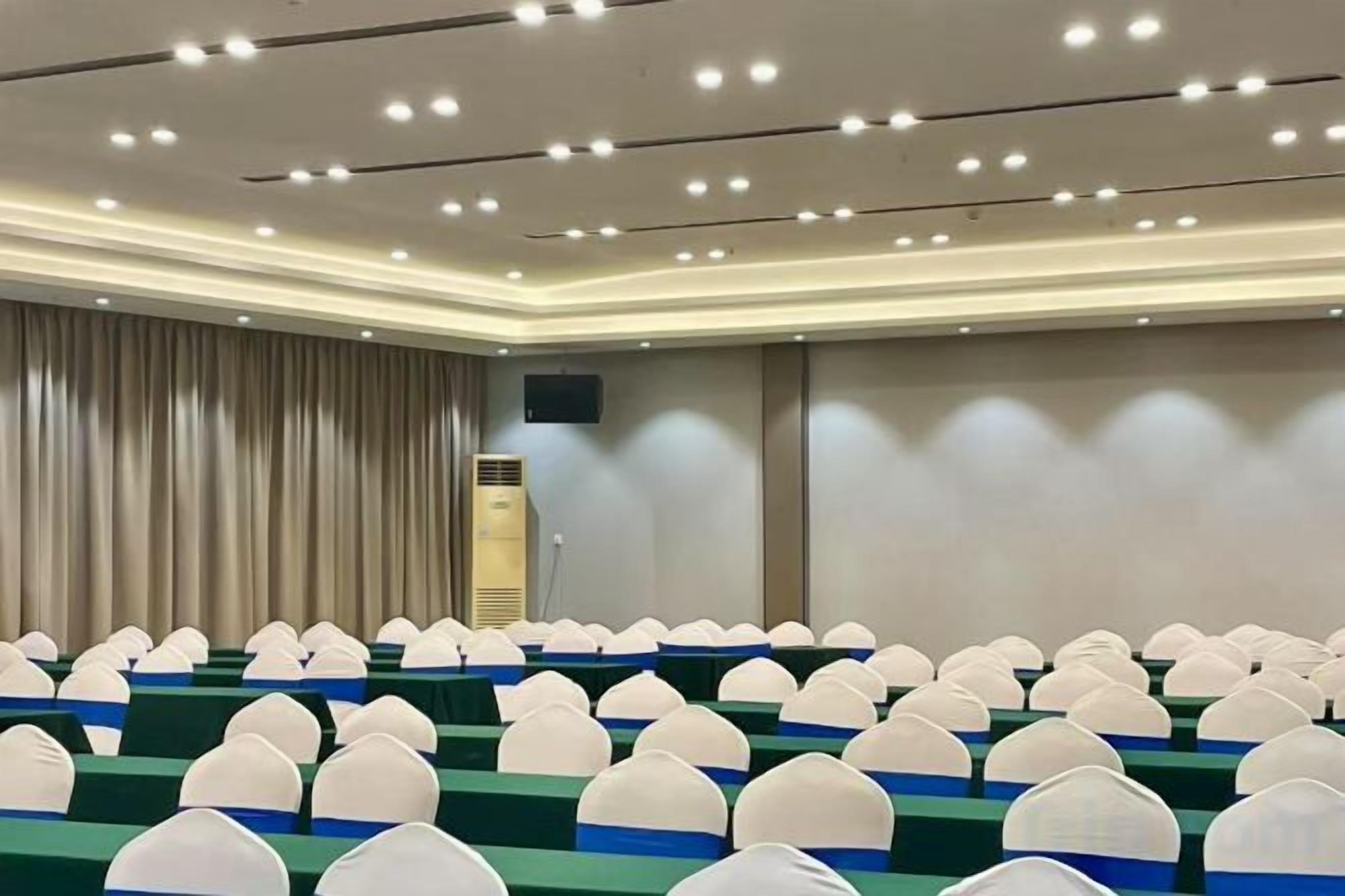 A conference room with rows of chairs, a podium, and a curtain backdrop.