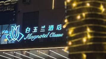 A hotel sign with illuminated text and a logo.