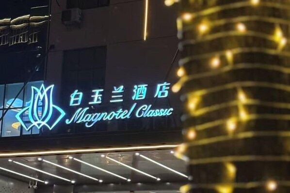 Un letrero de hotel con texto iluminado y un logotipo.
