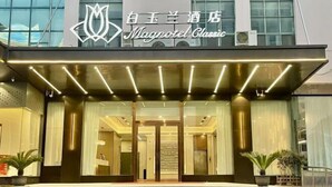 The exterior of a hotel with a modern facade, a prominent entrance with glass doors, and a sign reading "Magnotel Classic". - Magnotel Hotel (Yangzhou East High Speed Railway Station) (Yangzhou)