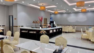 Un salón de conferencias de hotel con una isla central, mesas redondas y sillas.