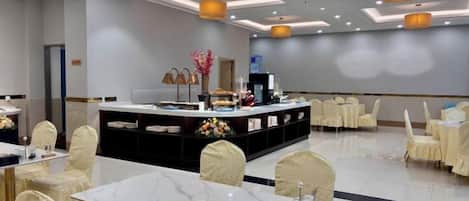Un salón de conferencias de hotel con una isla central, mesas redondas y sillas.