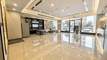 Un hall espacioso con diseño moderno, que incluye un mostrador de recepción, una zona de estar y amplias ventanas.
