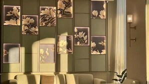 A modern living room with a sofa, a coffee table, and decorative wall panels with floral designs. - Magnotel Hotel (Yangzhou East High Speed Railway Station) (Yangzhou)