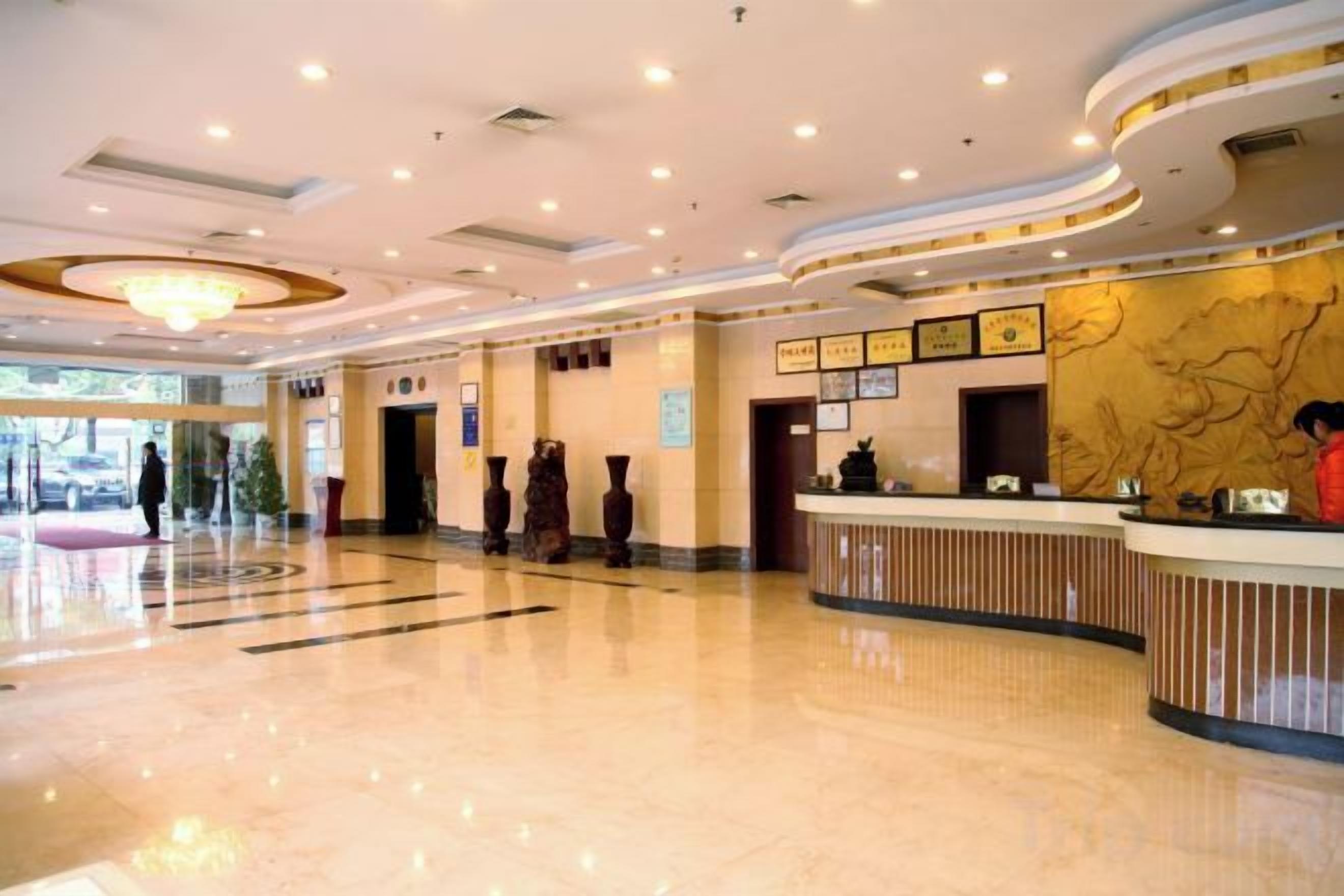 Un hall d’hôtel avec un comptoir d’accueil, un lustre et une grande fenêtre.