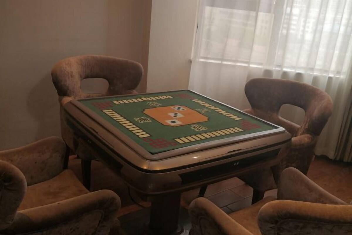A square table with a green and orange board game, surrounded by four brown chairs.