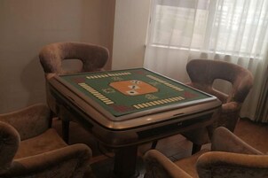 A square table with a green and orange board game, surrounded by four brown chairs.