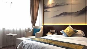 A hotel room with a bed, a chair, a small round table, and a wall with a decorative panel.