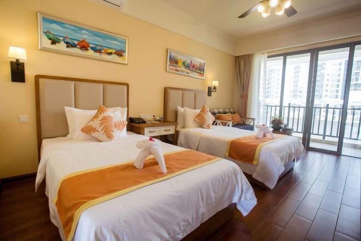 A hotel room with two beds, each with a headboard, a nightstand, a lamp, and a painting on the wall.