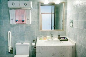 Un baño con lavamanos blanco, espejo e inodoro.