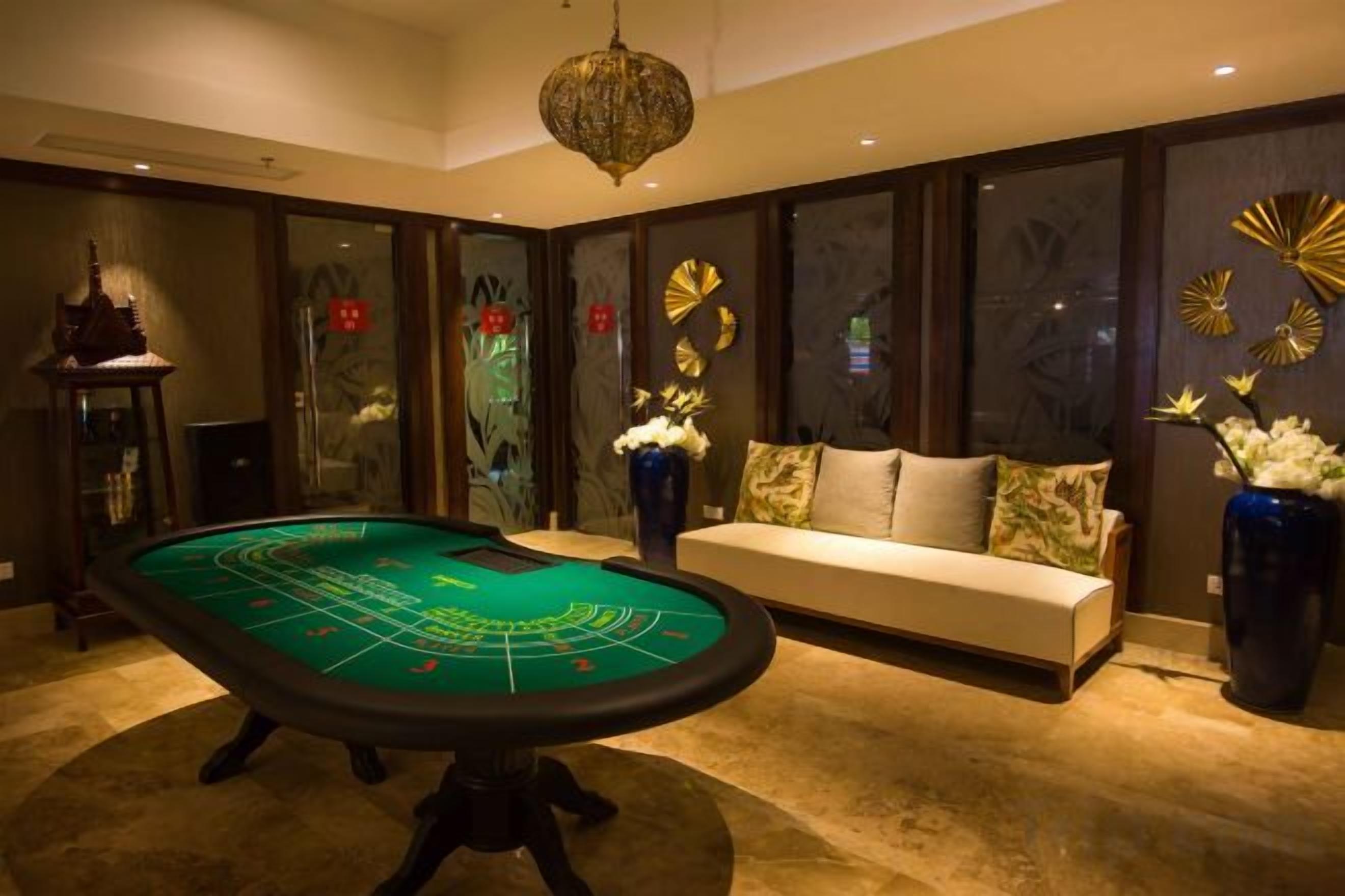 A room with a craps table, a sofa, and decorative elements like a vase and wall art.