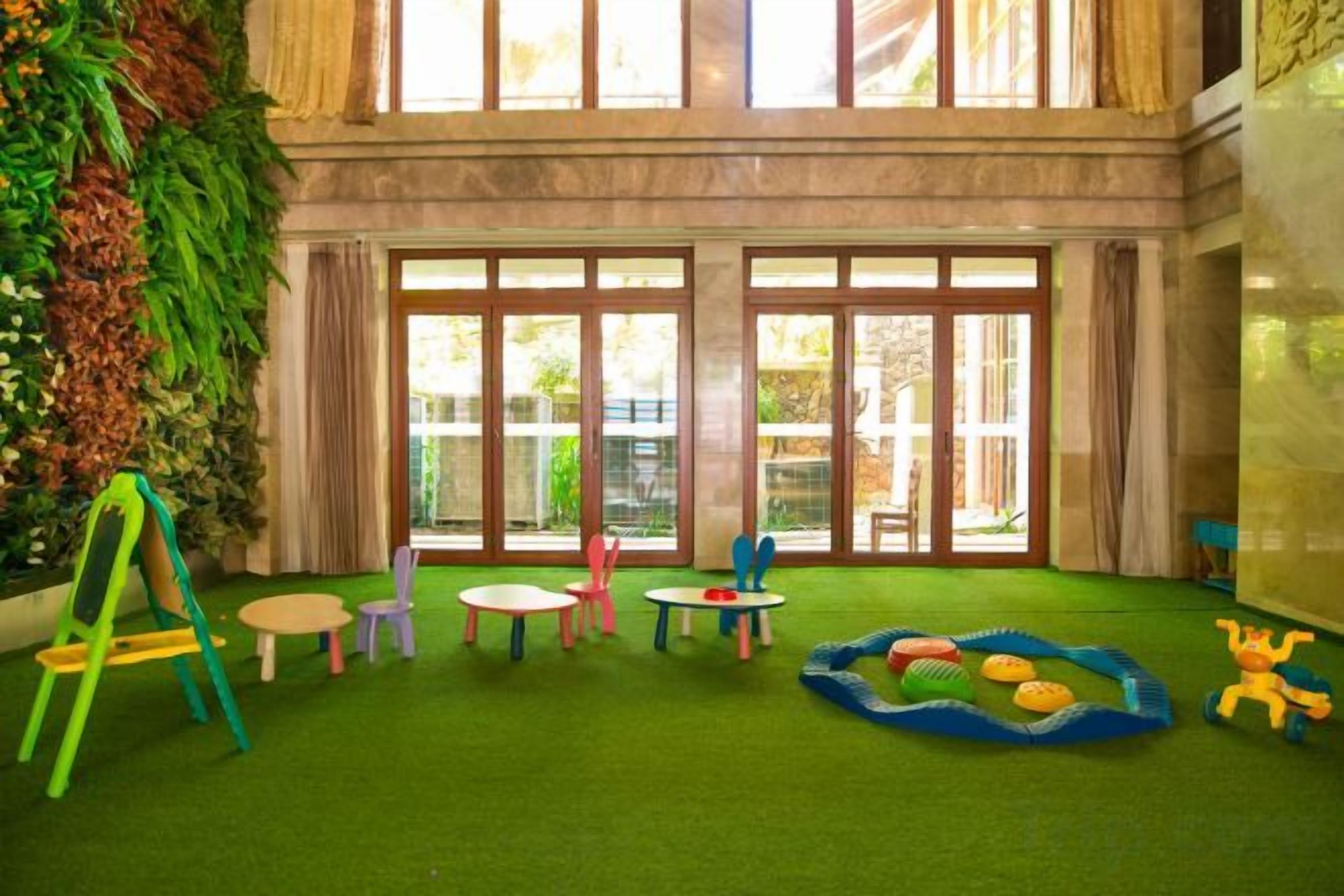 A children's play area with artificial grass, play tables, and a swing set.