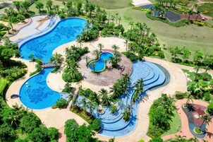 Un resort con varias piscinas, palmeras y un campo de golf.
