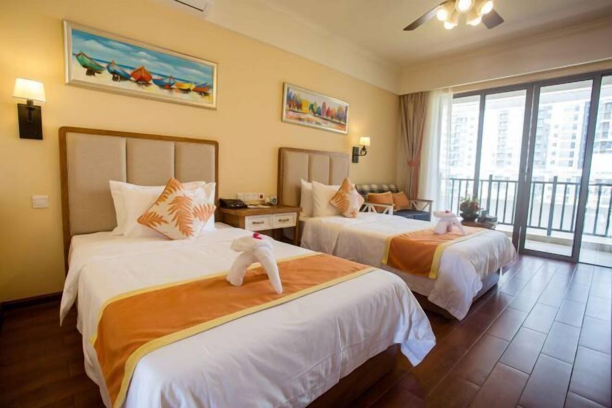 A hotel room with two beds, a balcony, and artwork on the walls.