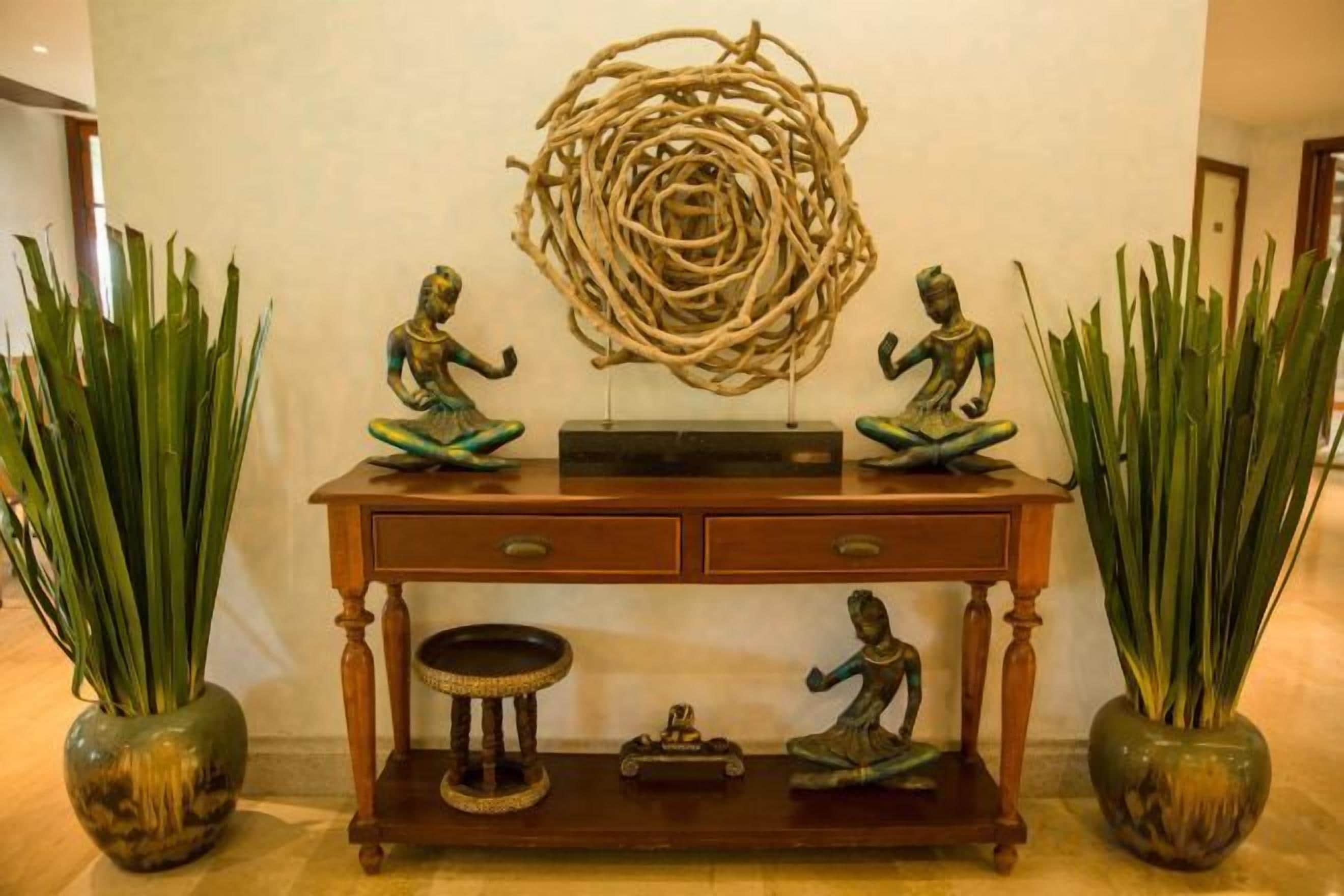 A console table with decorative items, including statues and a woven sculpture.