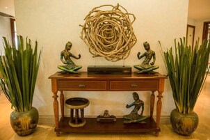 A console table with decorative items, including statues and a woven sculpture.