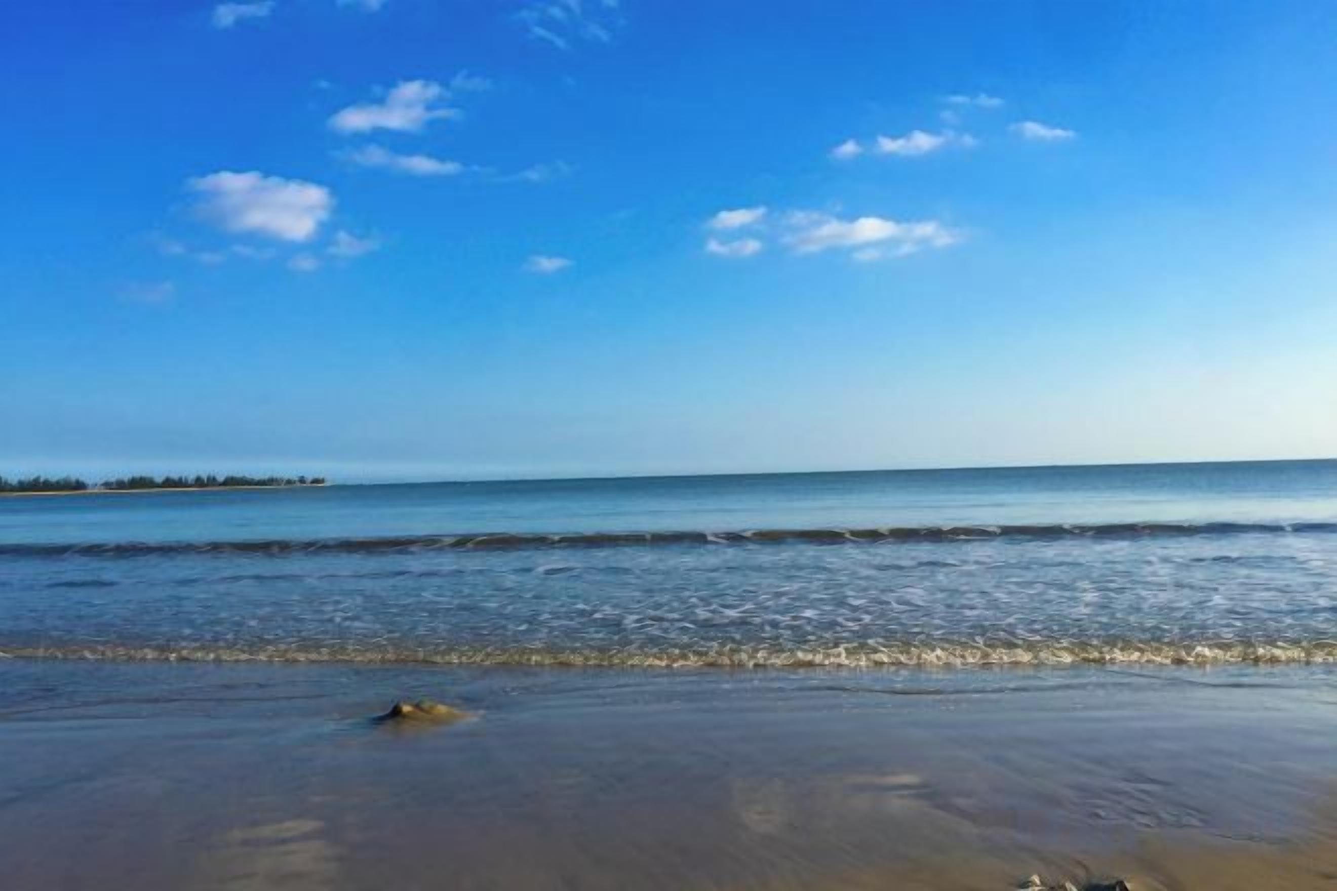 A beach with a clear sky and calm sea.