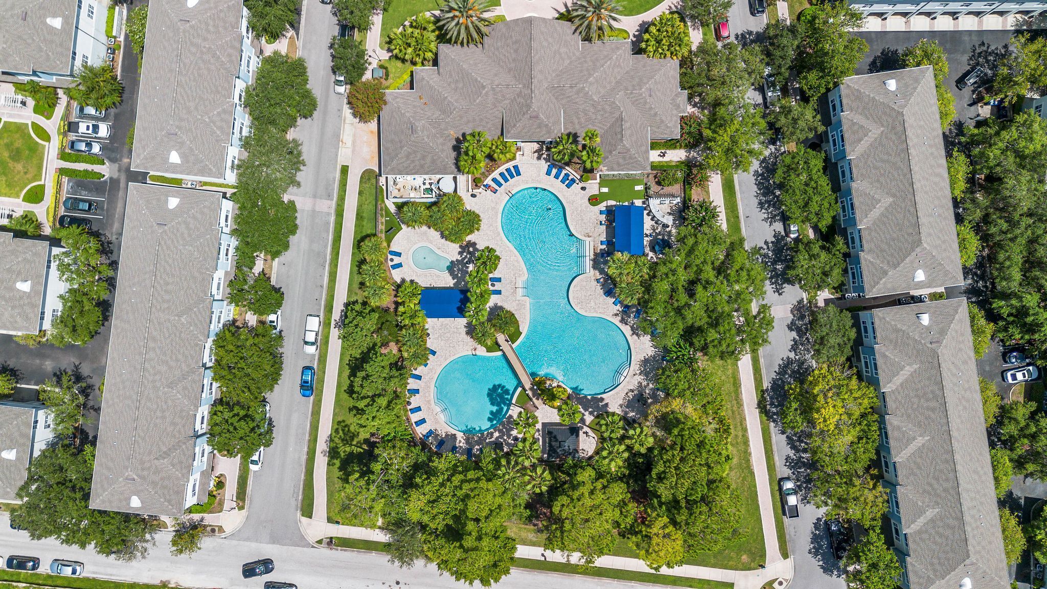 Vista aérea de una zona residencial con una piscina central rodeada de casas y vegetación.
