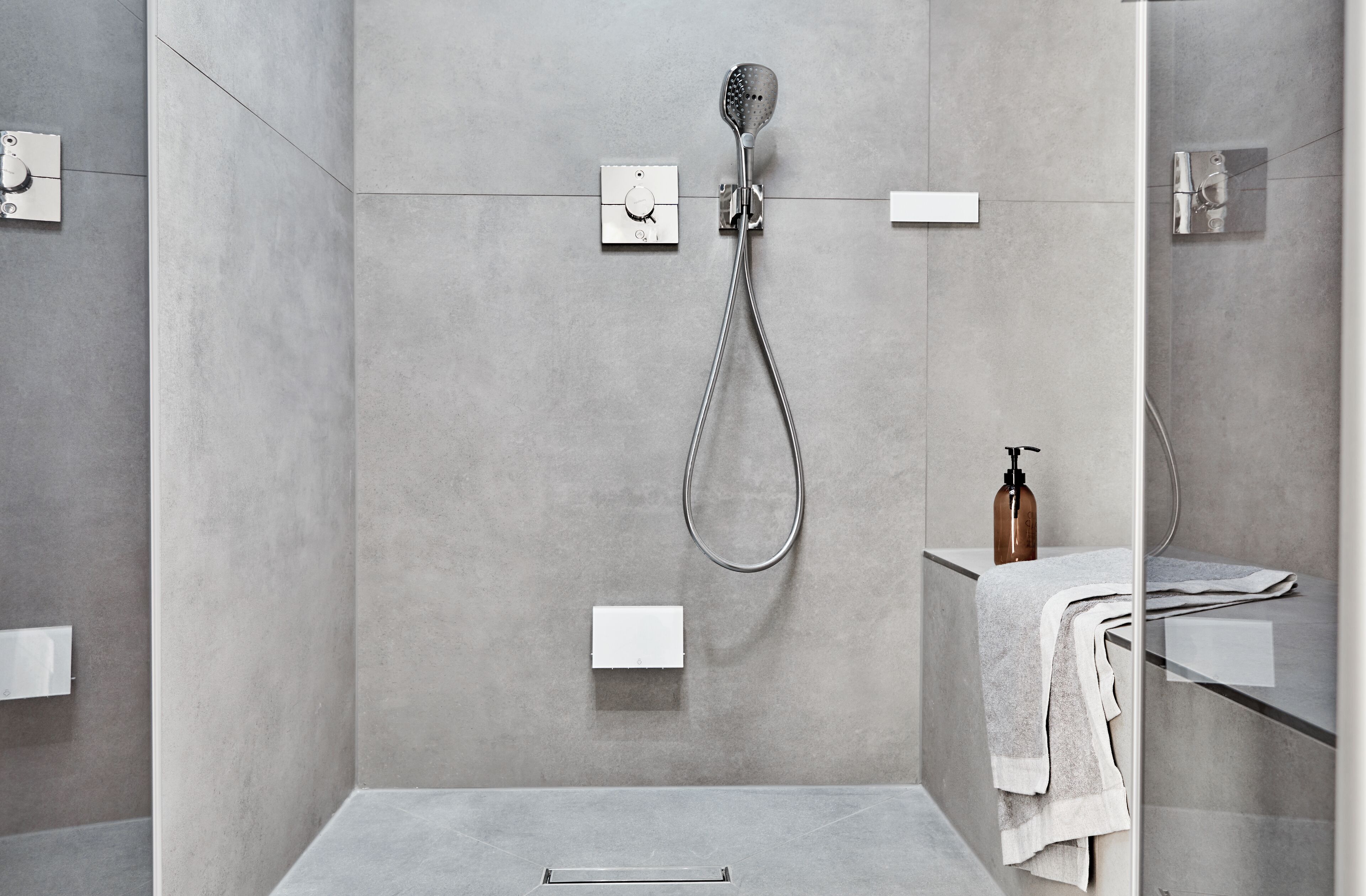 A modern shower with a handheld showerhead and a wall-mounted control panel.
