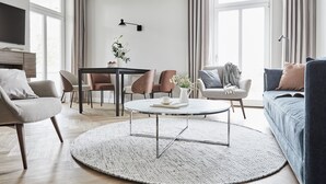 Ein modernes Wohnzimmer mit rundem Couchtisch, einer Couch und einem Essbereich mit Stühlen und Tisch.