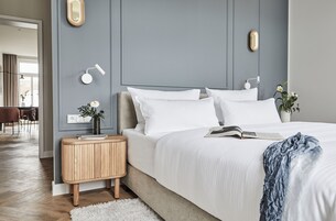 Un dormitorio moderno con una cama grande, mesitas de noche y vistas al área de comedor.