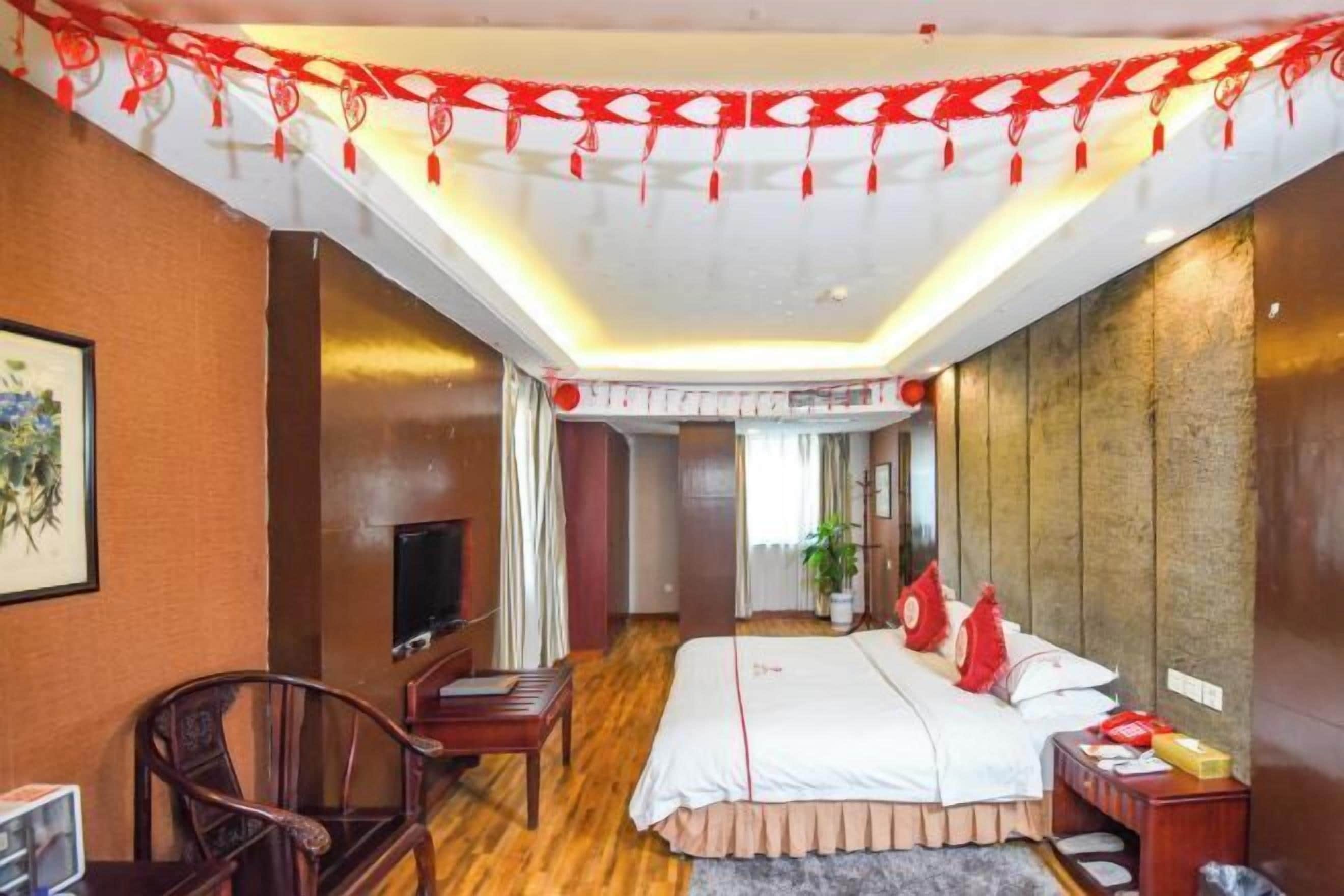 A hotel room with a bed, a TV, a desk, and a chair.