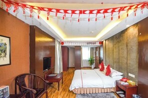 Ein Hotelzimmer mit Bett, Fernseher, Schreibtisch und Stuhl.