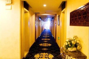 Un pasillo de hotel con alfombra estampada, puertas a ambos lados y un adorno en la pared.