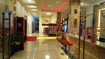 Un'accogliente hall d'albergo con reception, area relax e una scala che conduce ai piani superiori.