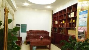 Une pièce comprenant un canapé en bois, une table basse et une bibliothèque remplie de livres et d’objets décoratifs.